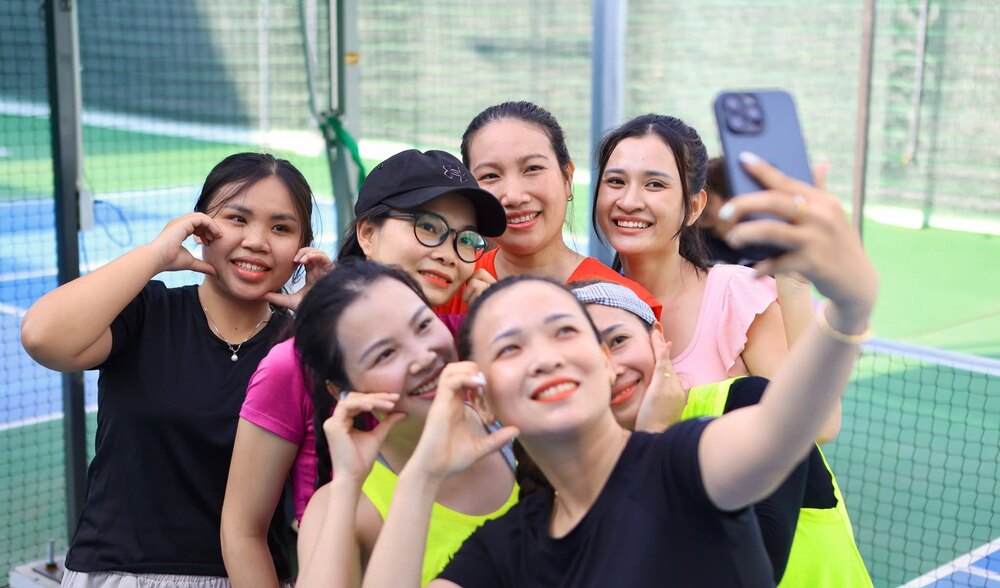 Sáu thành viên nữ của câu lạc bộ chụp ảnh selfie cùng nhau trên sân pickleball sau buổi tập.